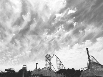 Low angle view of rides against clouds