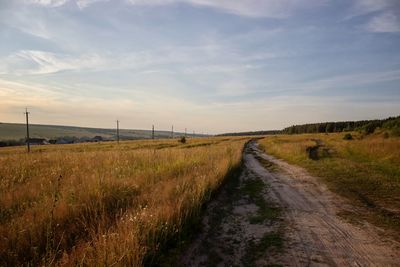 Road amidst field against sky