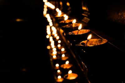 Row of lit diyas in dark