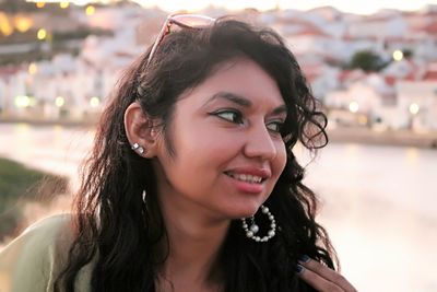 Close-up of woman smiling against river during sunset