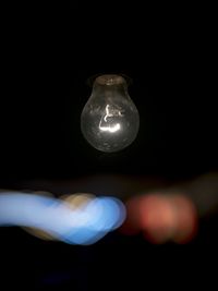 Close-up of illuminated light bulb against black background