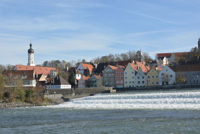 Houses by sea against sky in town