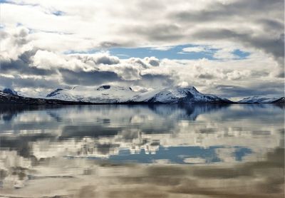 Scenic view of lake by snowcapped mountains against sky