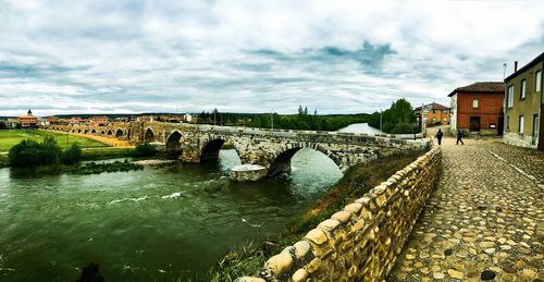 Bridge over river against cloudy sky