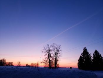 Scenic view of snow covered field against sky at sunset