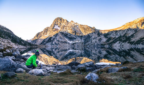 Man sitting on rock against mountains