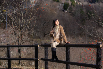 Portrait of young woman standing by railing