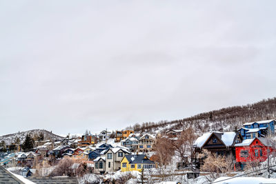 Houses by snow covered town against sky