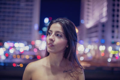 Young woman looking away at illuminated city