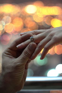 Cropped image of bridegroom putting ring on bride finger