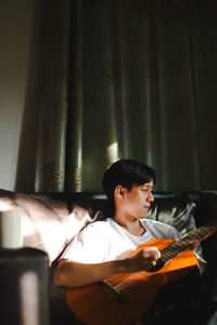 Young man sitting and playing guitar 