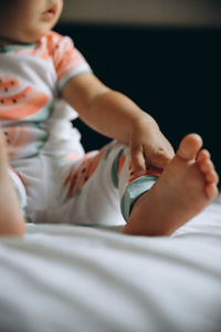 Low section of baby boy lying on bed at home