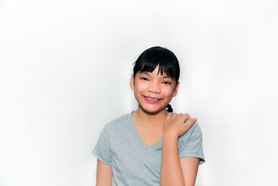 Portrait of smiling girl standing against white background