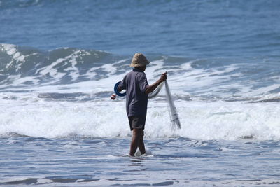 Rear view of man standing in sea