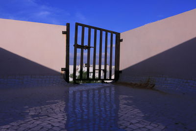 Metallic structure on footpath against blue sky