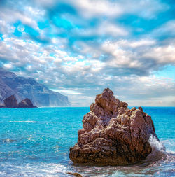 Rock formation in sea against sky