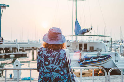 Rear view of woman standing at harbor against sky