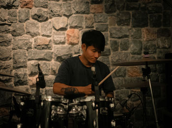 Full length of a young man playing piano against brick wall