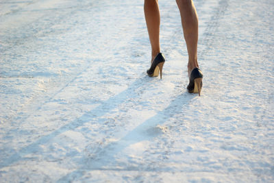 Cropped photo of female legs in shoes on snow. selective focus.