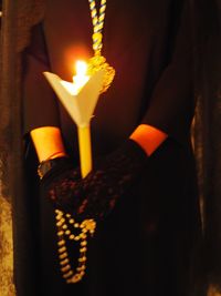 Close-up of hand holding lit candles