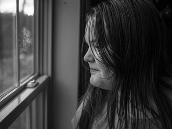 Close-up of girl looking through window at home