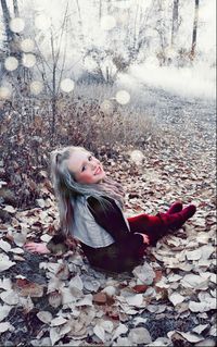 Portrait of young woman lying on land during autumn