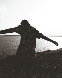 Woman standing by sea against clear sky