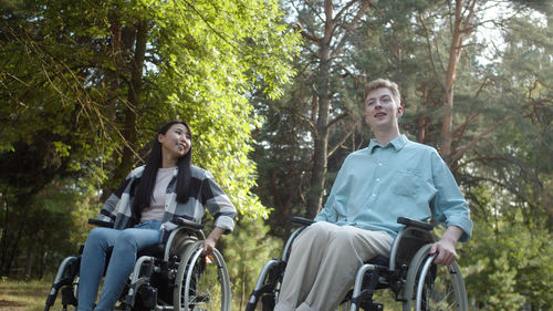 Portrait of smiling friends with bicycles against trees