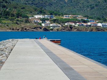 People on sea by buildings against mountain