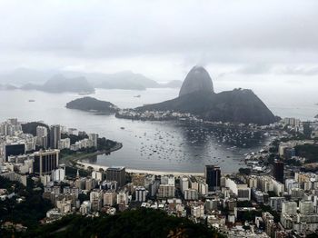 High angle view of city by sea against sky