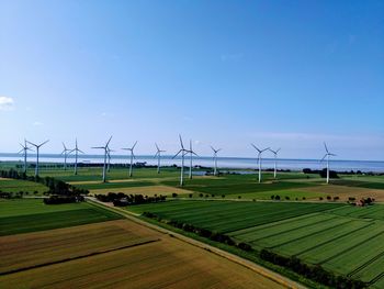Wind turbines on field against sky