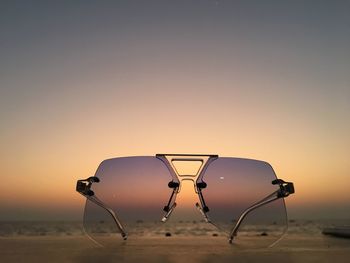 Electric light on beach against clear sky during sunset