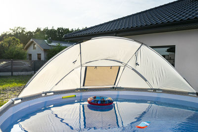 A large expansion pool with a diameter of 3.96 with a canopy, set in the backyard next to the house.