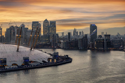 Scenic view of river and buildings against sky during sunset