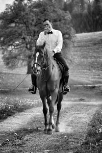 Man smoking cigarette while riding horse