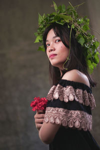 Portrait of beautiful young woman standing against plants