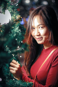 Portrait of young woman by christmas tree