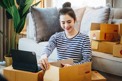 Portrait of smiling woman using laptop while sitting on sofa at home