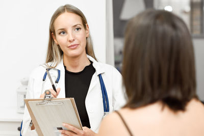 Smiling female doctor having discussion with patient at clinic