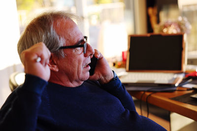 Man using mobile phone while sitting on table