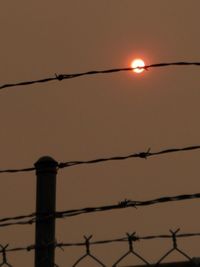 Silhouette of barbed wire against sky during sunset