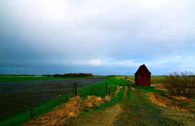 Scenic view of field by building against sky