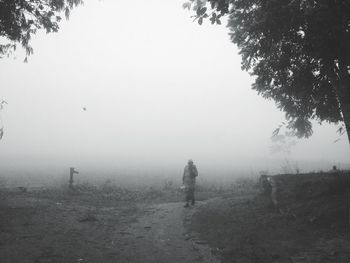 Man walking on landscape in foggy weather