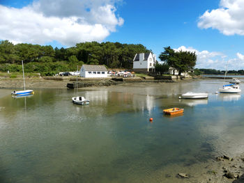 Boats moored on lake by buildings against sky