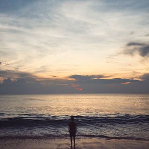 Silhouette man standing on beach against sky during sunset
