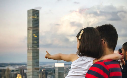 Rear view of people standing on city against sky