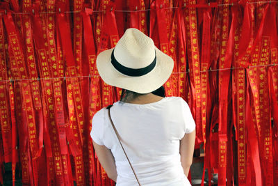 Rear view of woman standing against red ribbons for sale in market