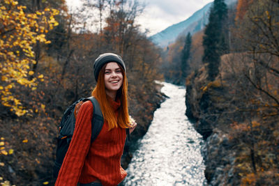 Portrait of smiling young woman in forest during winter