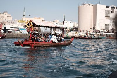 People on boats in sea against buildings
