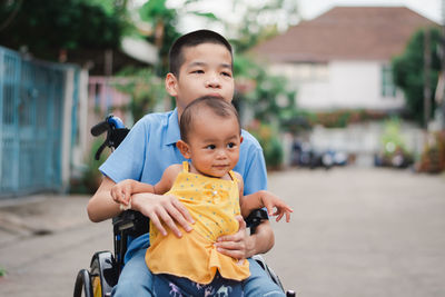 Disable boy holding cute sister while sitting on wheelchair